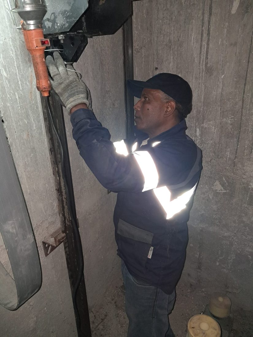 Technicien TGI travaillant en hauteur dans la gaine d'ascenseur