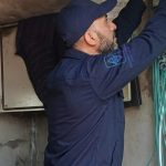 Technicien TGI câblant un coffret électrique d'ascenseur