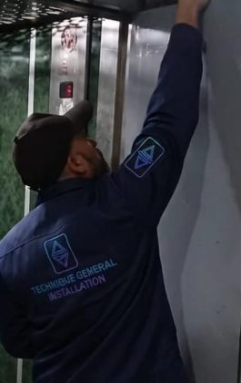 Technicien TGI installant une porte palière d'ascenseur neuve