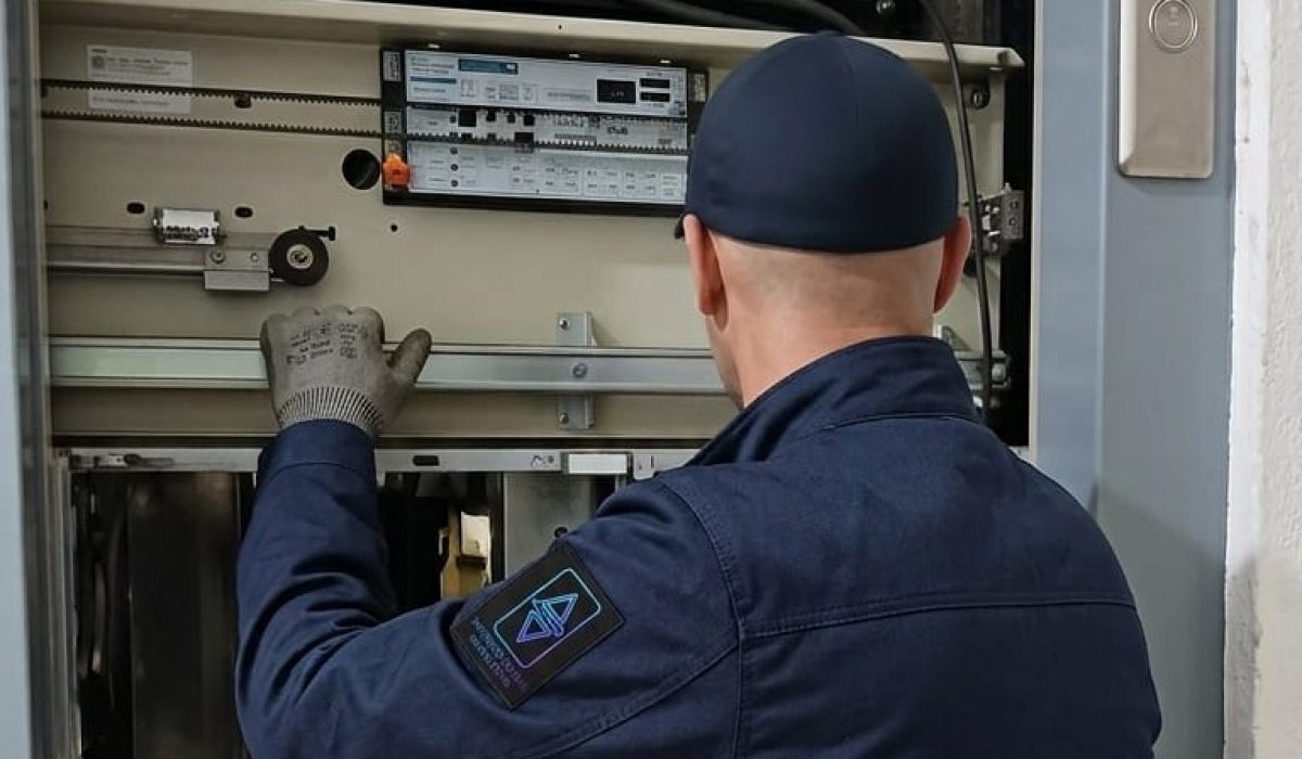 Technicien TGI réglant un coffret de commande en gaine d'ascenseur