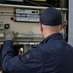 Technicien TGI réglant un coffret de commande en gaine d'ascenseur