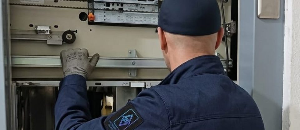 Technicien TGI réglant un coffret de commande en gaine d'ascenseur